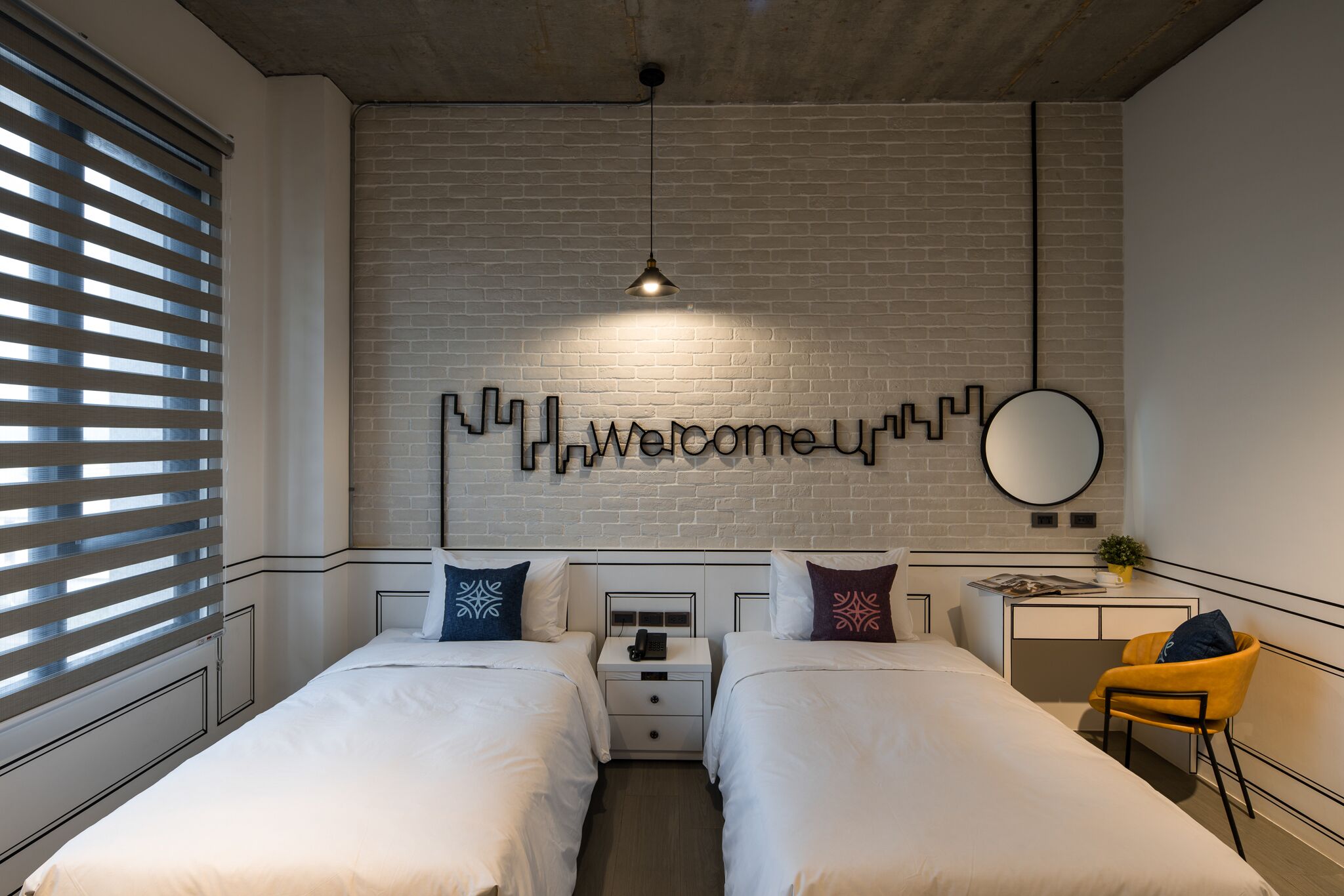 Una habitación de hotel moderna con dos camas, un escritorio y un espejo grande instalado en la pared.