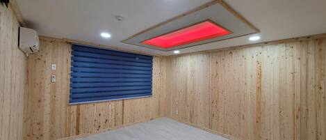 A room with wooden panel walls, a blue sliding door, a recessed ceiling light, and a red under-cabinet light.