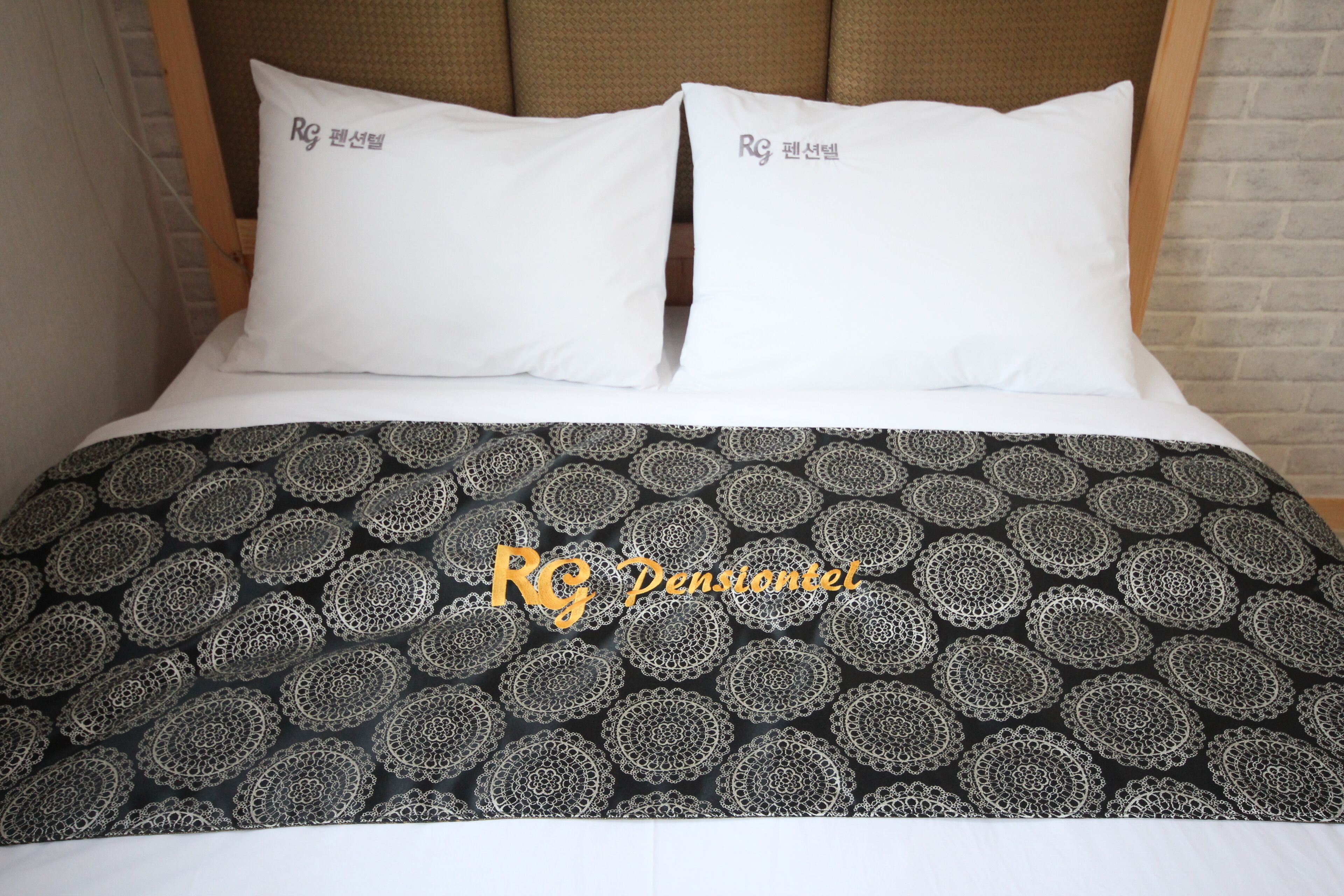 A bed with two white pillows and a black and white patterned bedspread.