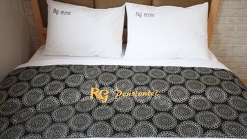 A bed with two white pillows and a black and white patterned bedspread.