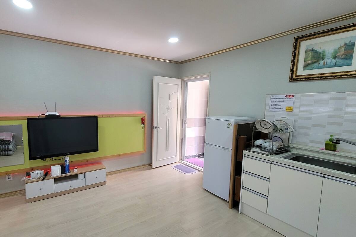 A compact kitchen with a built-in TV, a refrigerator, and a sink.