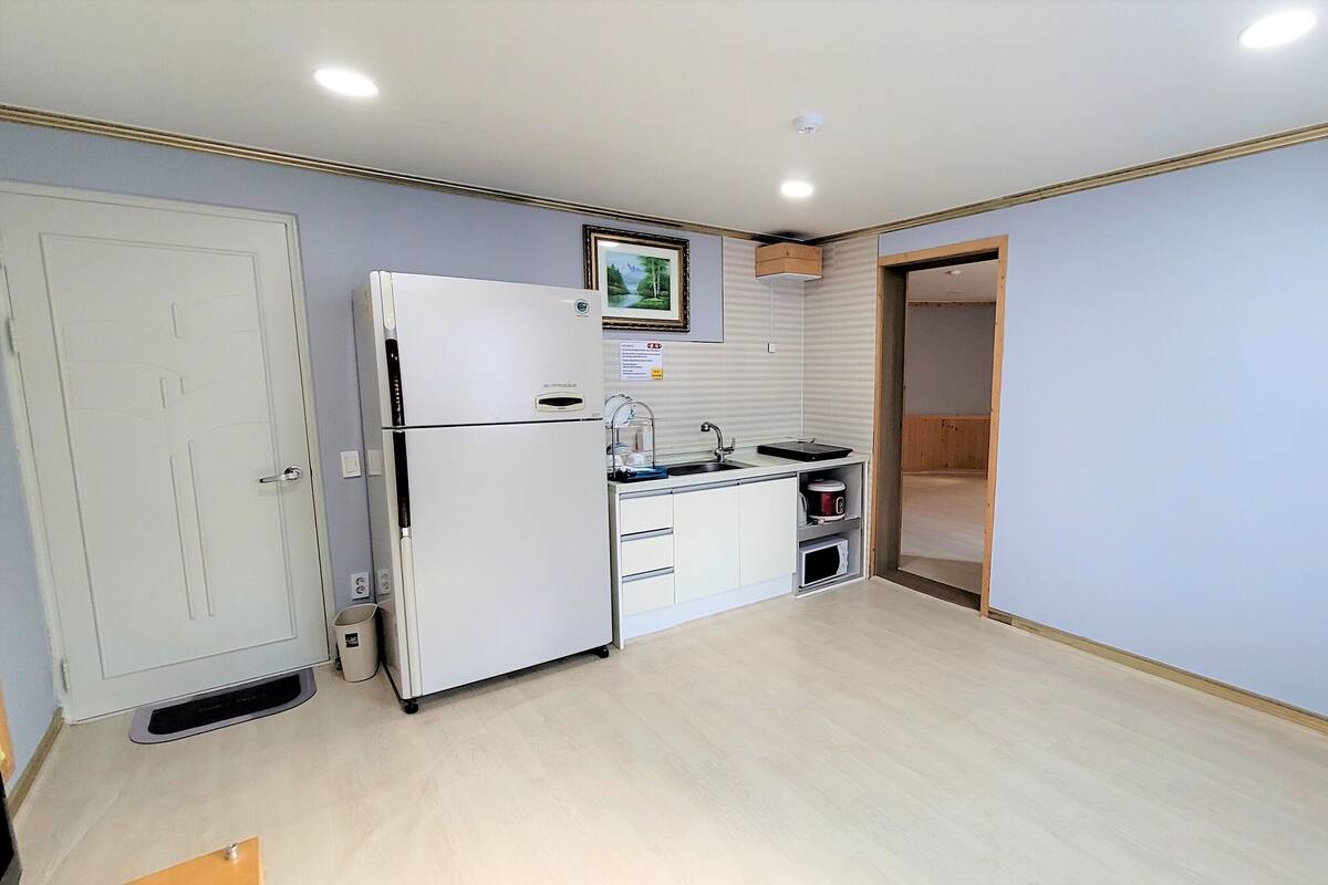 A compact kitchen with a refrigerator, sink, and microwave.