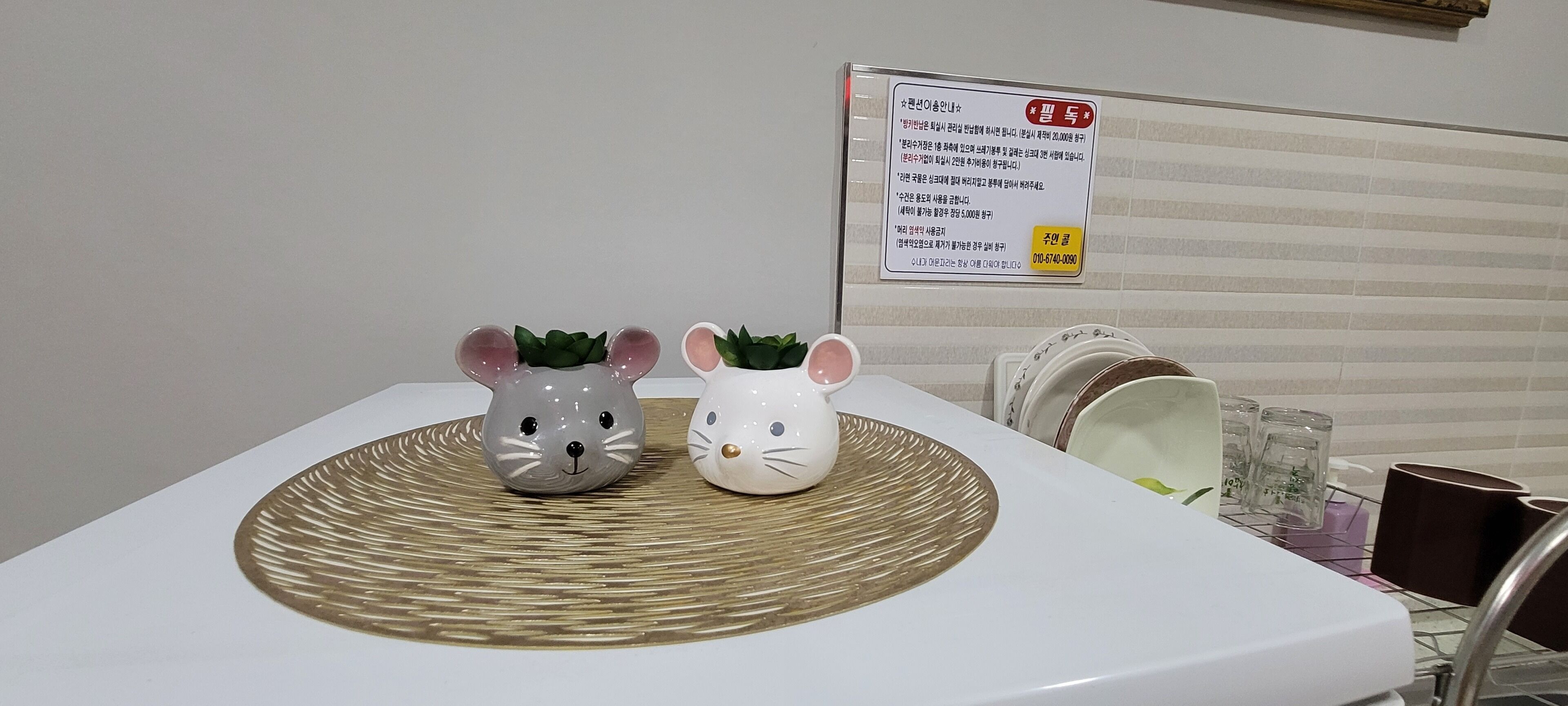 A bathroom sink with two ceramic mouse figurines and a woven mat.