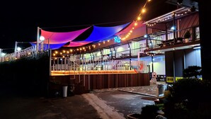 Ein mehrstöckiges Restaurant im Freien mit überdachter Sitzgelegenheit und sichtbarer Treppe.