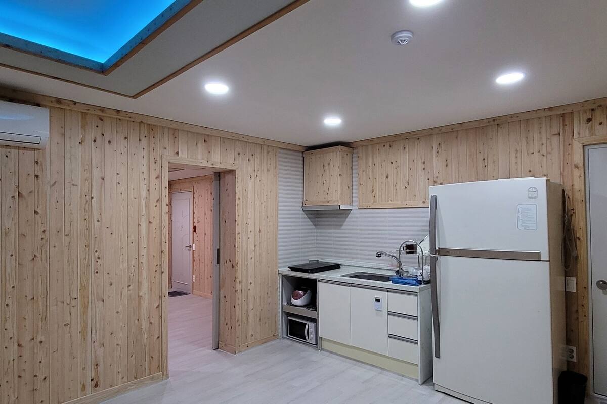 A kitchen with wooden paneling, a built-in sink, a refrigerator, and a skylight.