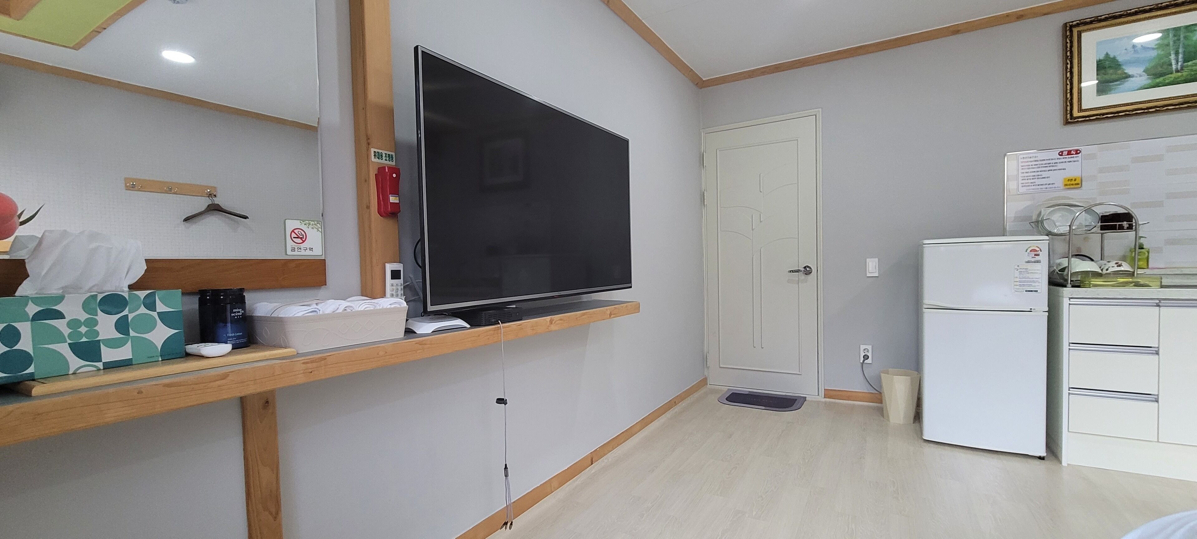 Una cocina compacta con un televisor de pantalla plana grande, un refrigerador y un microondas.
