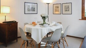 A dining area with a round table set for four, white tablecloth, and modern chairs.