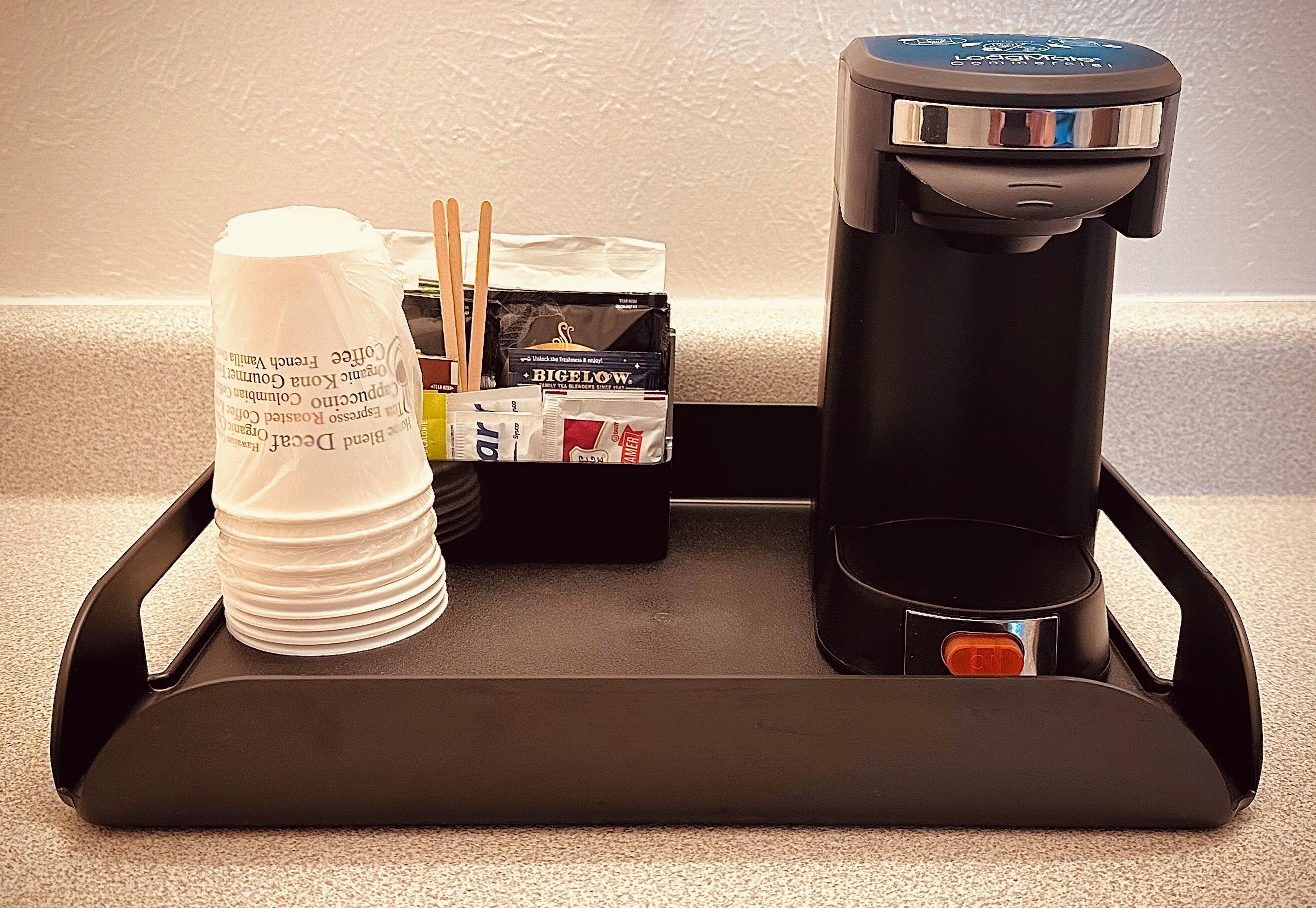 Una bandeja con una cafetera, una pila de tazas blancas y una caja de cigarrillos Big Flow.