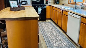 Una cocina con armarios de madera, microondas, estufa y lavavajillas.