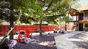 Un patio al aire libre con sillas rojas, un sendero de concreto y una cerca roja.