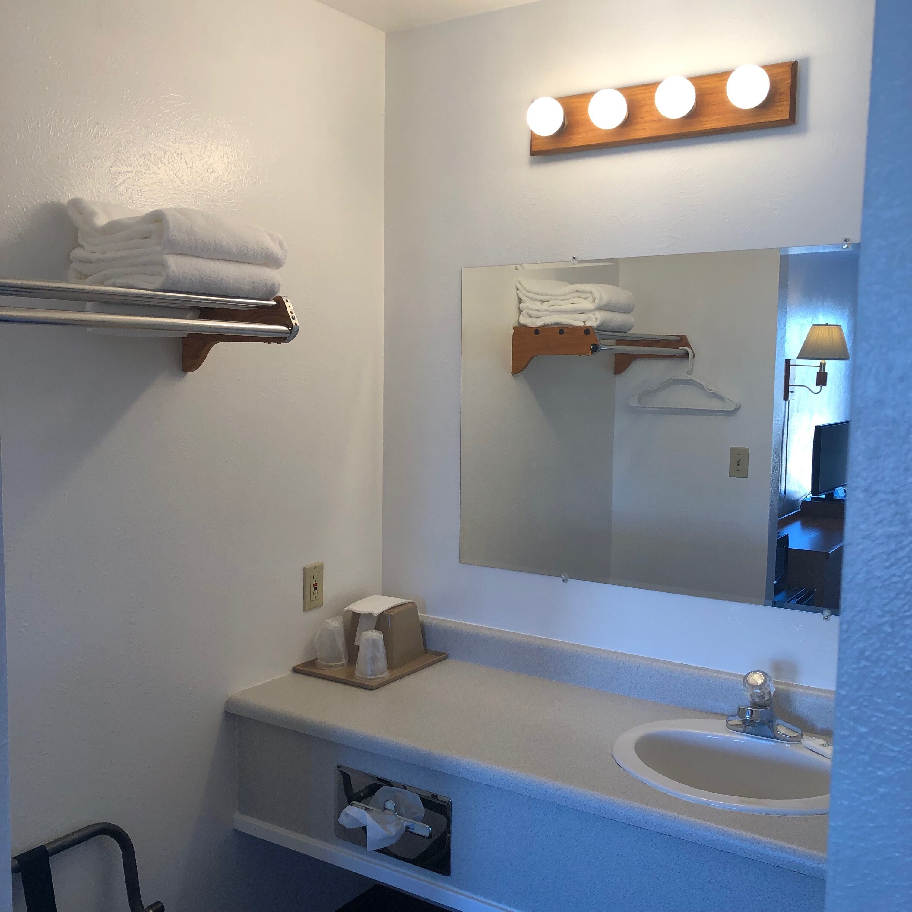 Une salle de bain équipée d’un lavabo, d’un miroir, d’un porte-serviettes et d’une étagère où sont rangés les articles de toilette.
