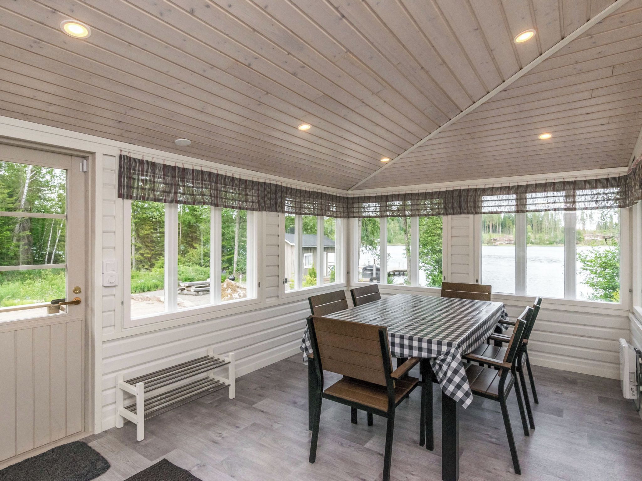 Un comedor techado con mesa para seis, ventanas amplias y vista al exterior.