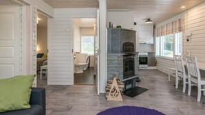 A spacious living area with a fireplace, a dining table, and a kitchen in the background.