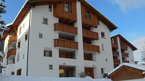 A multi-story building with wooden balconies and a white facade. - Chesa Maurus A1 by Interhome (St. Moritz)