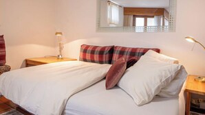 A bedroom with a bed, a nightstand, a lamp, and a mirror on the wall. - Chesa Maurus A1 by Interhome (St. Moritz)