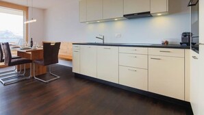Eine moderne Küche mit weißen Schränken, einer schwarzen Arbeitsplatte und einem Essbereich mit einem Holztisch und Stühlen.
