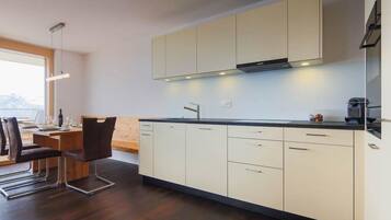 Eine moderne Küche mit weißen Schränken, einer schwarzen Arbeitsplatte und einem Essbereich mit einem Holztisch und Stühlen.