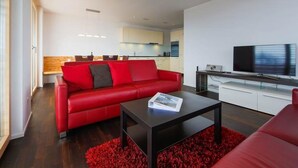 Ein modernes Wohnzimmer mit einem roten Sofa, einem schwarzen Couchtisch und einem Flachbildfernseher.