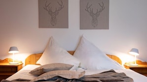 Camera da letto con testiera in legno, due cuscini bianchi, coperta grigia e due abat-jour.