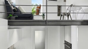 Eine moderne Wohnung mit Balkon, einer Küche und einem Wohnbereich mit Sofa und Zimmerpflanzen.