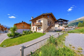 A mountain lodge with a wooden exterior, a paved driveway, and a view of the surrounding landscape.