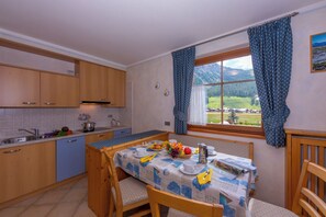 A kitchen with wooden cabinets, a dining table set with plates, cups, and a fruit bowl.