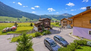 A mountain village with wooden buildings, a parking area, and a view of the surrounding hills. - Ginevra, Livigno, Italy (Livigno)