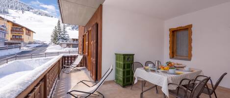 A balcony with a table set for breakfast, a chair, and a green cabinet.