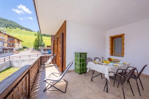A balcony with a table set for breakfast, overlooking a green landscape.