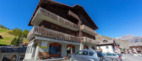 A two-story building with balconies, a sign reading 'MODA GIOVANE,' and a car parked in front.