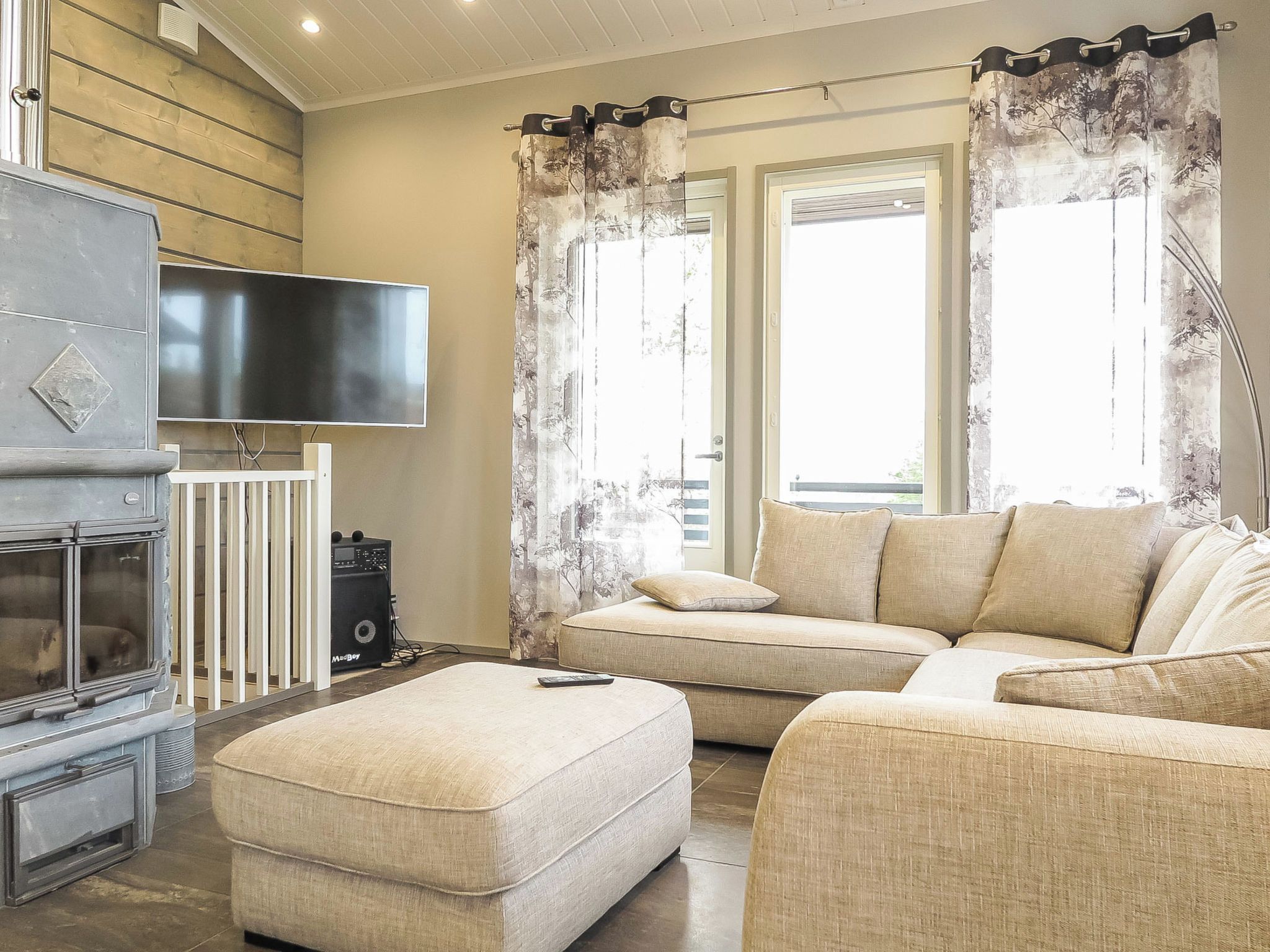 Un salon avec un téléviseur à écran plat fixé au mur, un canapé, un pouf et une cheminée.