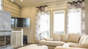 Ein Wohnzimmer mit Kamin, Sofa, Ottoman und Flachbildfernseher.