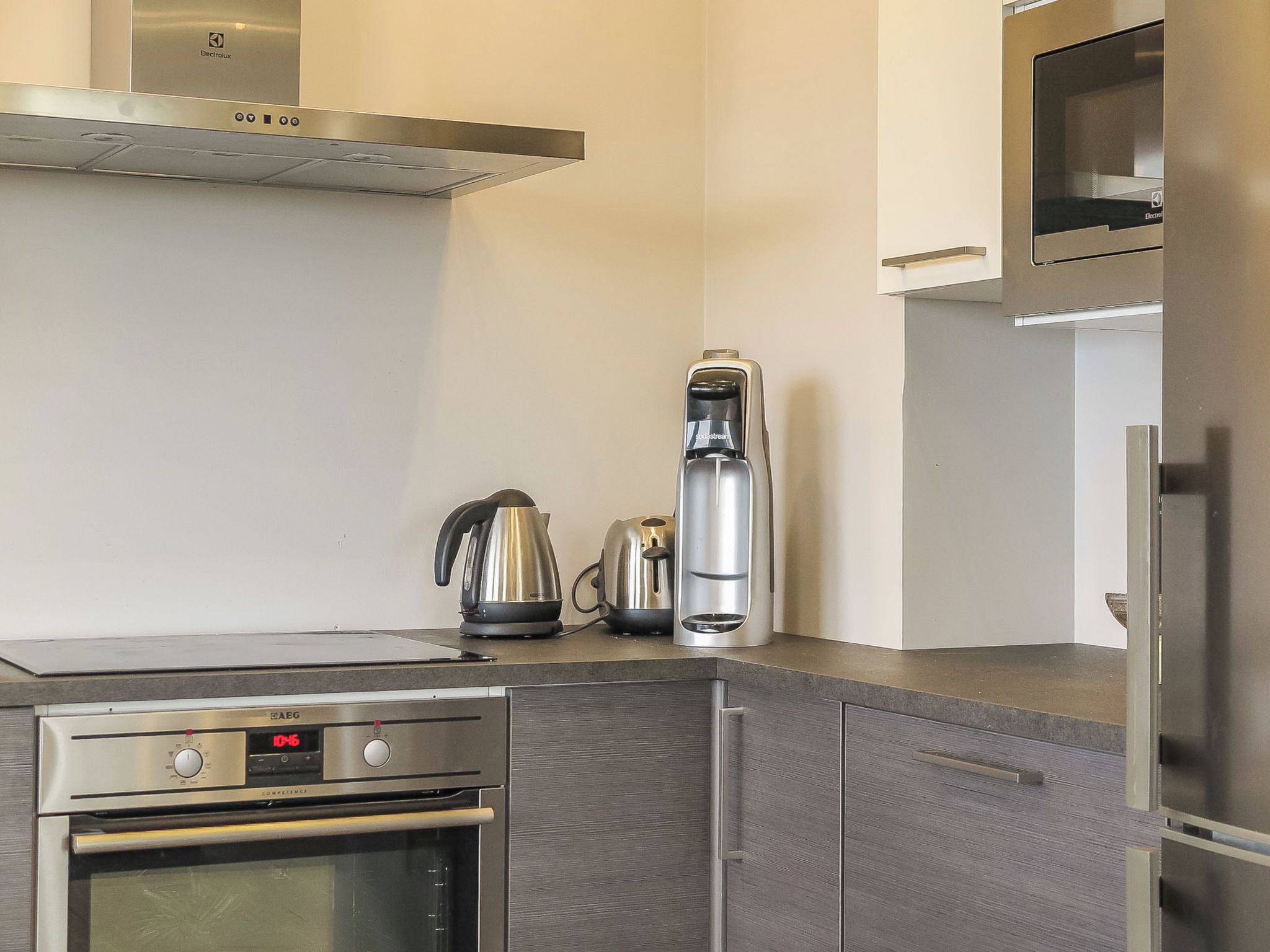 A modern kitchen with stainless steel appliances, including an oven, a coffee maker, and a kettle.