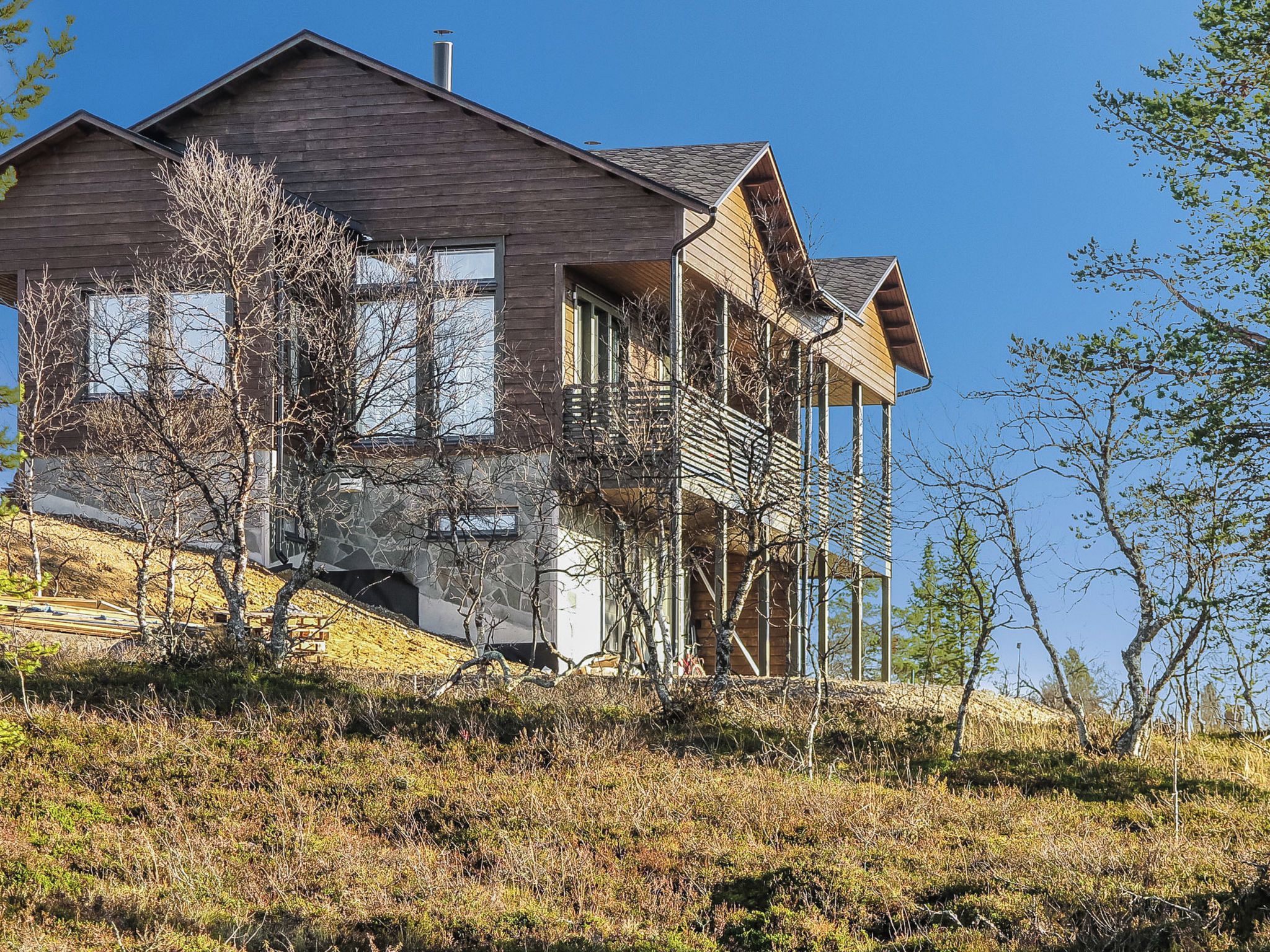 Une maison moderne à deux étages, dotée d’un toit en pente, de grandes fenêtres et d’un balcon.