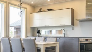 Eine moderne Küche mit grauen Schränken, einem Edelstahlbackofen und einem Essbereich mit Tisch und Stühlen.