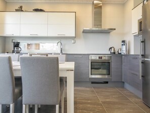 A modern kitchen with white cabinets, a stainless steel oven, and a refrigerator.