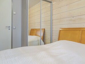A bedroom with a bed, a wooden headboard, a mirror, and a door.