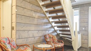 Eine Treppe mit Holzboden und weißer Geländer, die zu einem Raum mit grauer Wand und einer Tür führt.