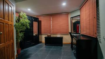 A hallway with a wooden door, a potted plant, a black cabinet, a black countertop, and a window with blinds.