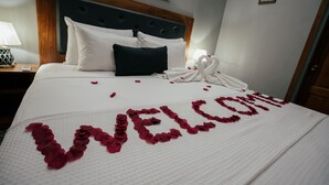 Une chambre d’hôtel avec un lit, des oreillers, une tête de lit, une table de chevet, une lampe et un tableau encadré au mur.