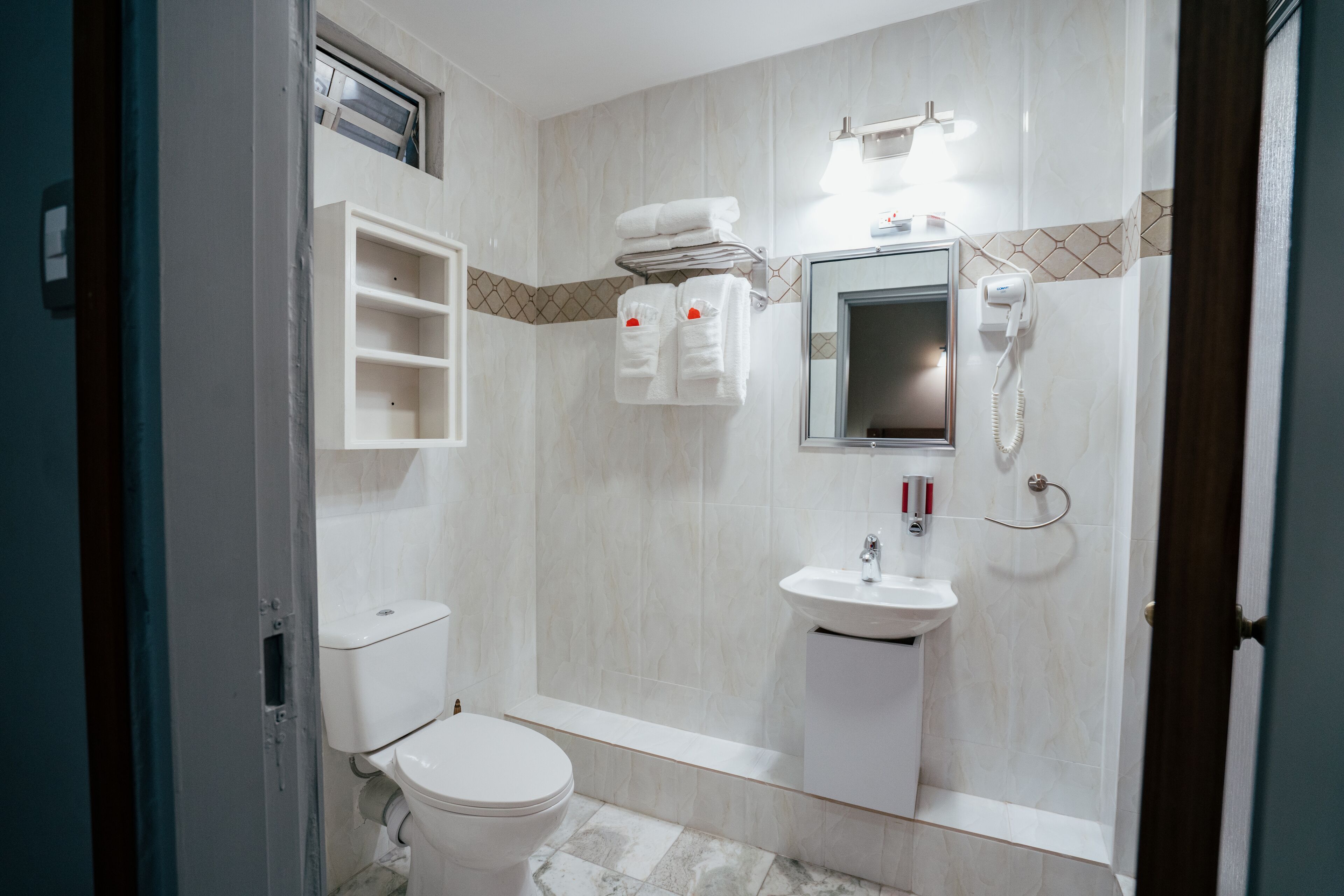 Een badkamer met toilet, wastafel en spiegel. Handdoekrek met handdoeken en een douchegordijn.