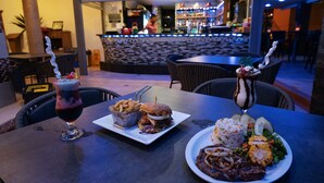 Une table à manger avec un hamburger, des frites, une salade et une boisson.