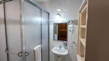 Une salle de bain avec une douche, un lavabo, un miroir et un porte-serviettes.