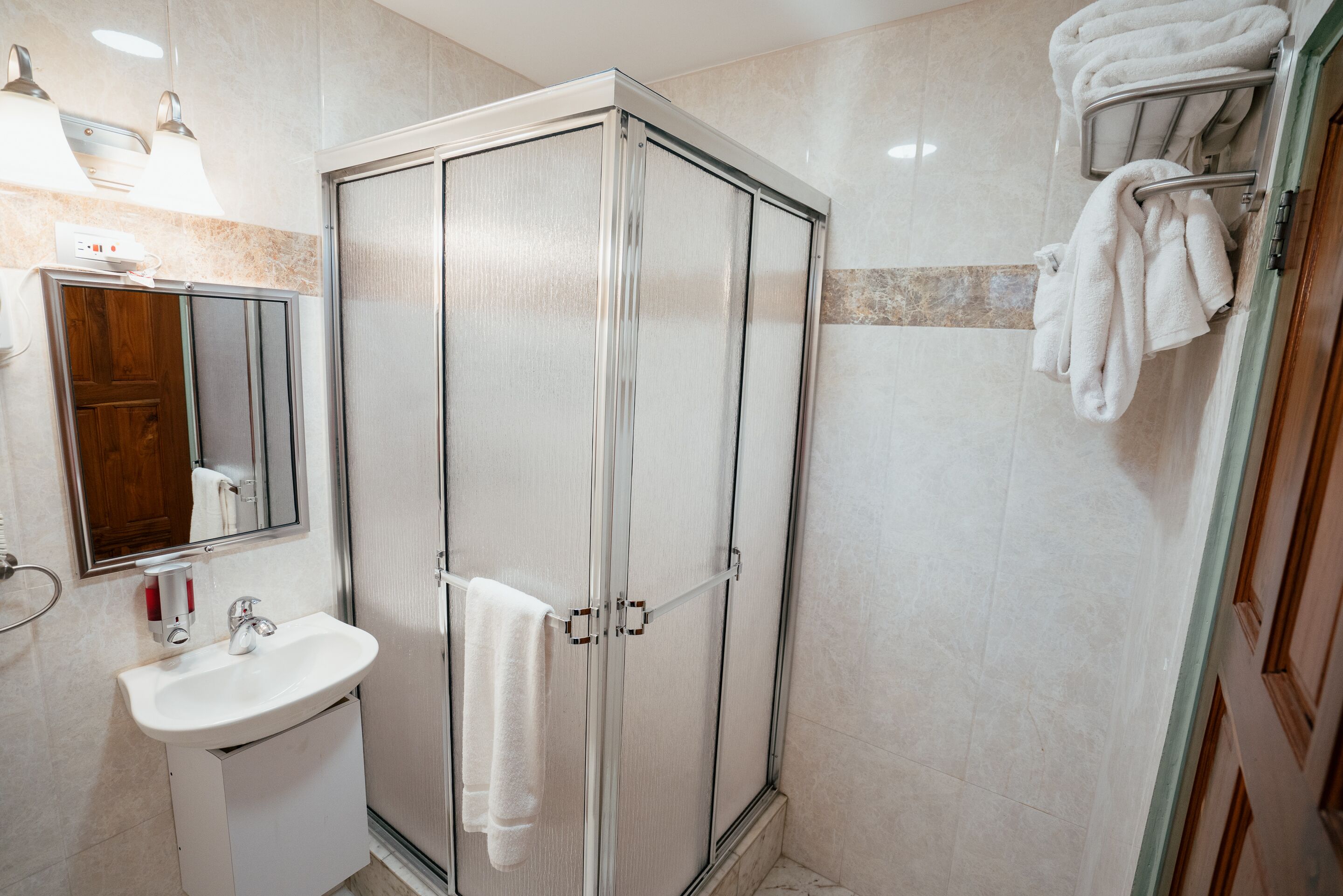 Une salle de bain moderne avec une douche à parois de verre, un lavabo et un porte-serviettes.
