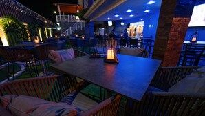 Un espace extérieur aménagé pour les repas, avec des meubles en osier et une table agrémentée d’un centre de table à bougie.