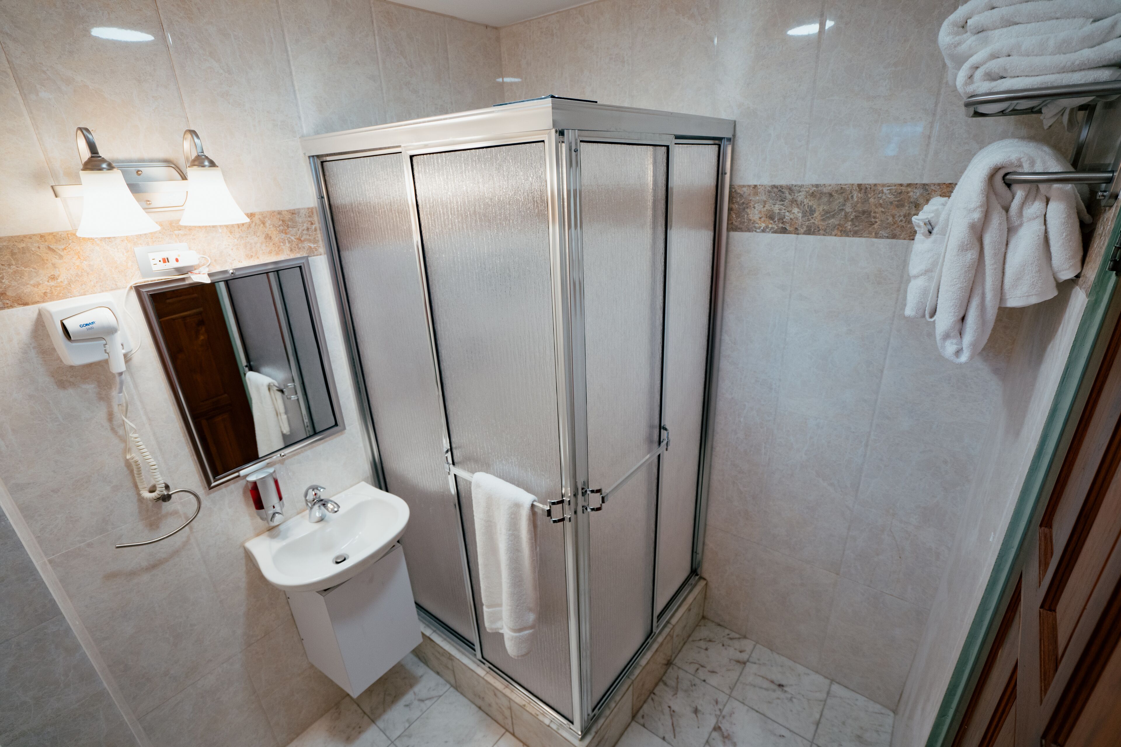 Ein modernes Badezimmer mit einer Duschkabine, einem Waschbecken, einem Spiegel und einem Handtuchhalter.