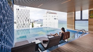 A poolside area with lounge chairs and a view of a cityscape and mountains. - Nalicas Hotel (Nha Trang)