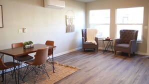 A modern living room with a wooden dining table, two armchairs, a sofa, and a small side table. - King Cottage in Downtown Meridian (Meridian)