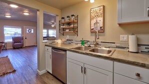 A modern kitchen with a double sink, stainless steel appliances, and a light-colored backsplash. - King Cottage in Downtown Meridian (Meridian)