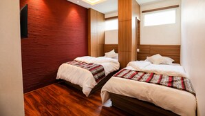 A hotel room with two beds, wooden flooring, a red accent wall, and a large window. - Flying Yak Hotel - Hostel (Kathmandu)